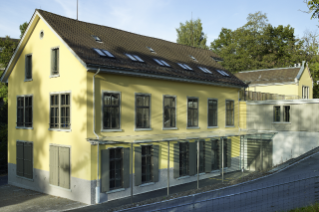 Die dunkelgelb renovierte Fassade des ehemaligen Fabrikgebäudes hebt sich von den umliegenden Wohnhäusern ab (© Theodor Stalder, Zürich)